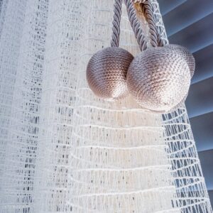 Close-up view of elegant white curtains with textured fabric and decorative tiebacks.