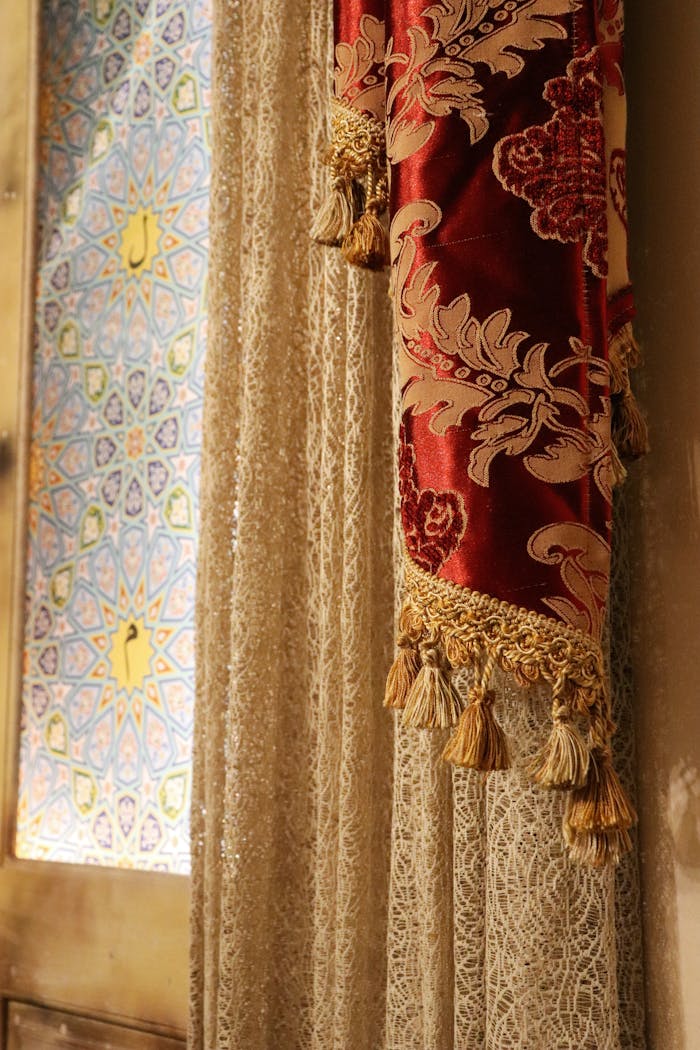 about-01 Elegant lace curtain with ornate red fabric beside colorful stained glass window.
